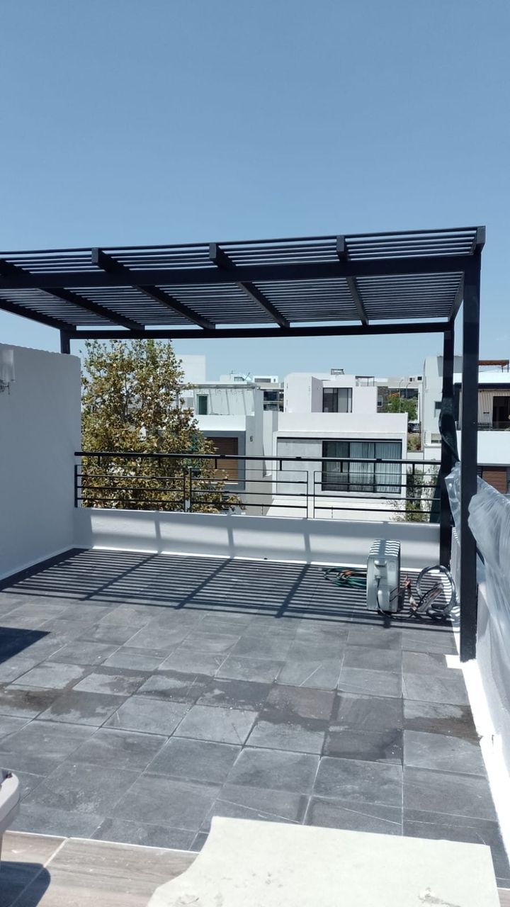 Pérgola metálica con barandal blanco instalada en terraza residencial