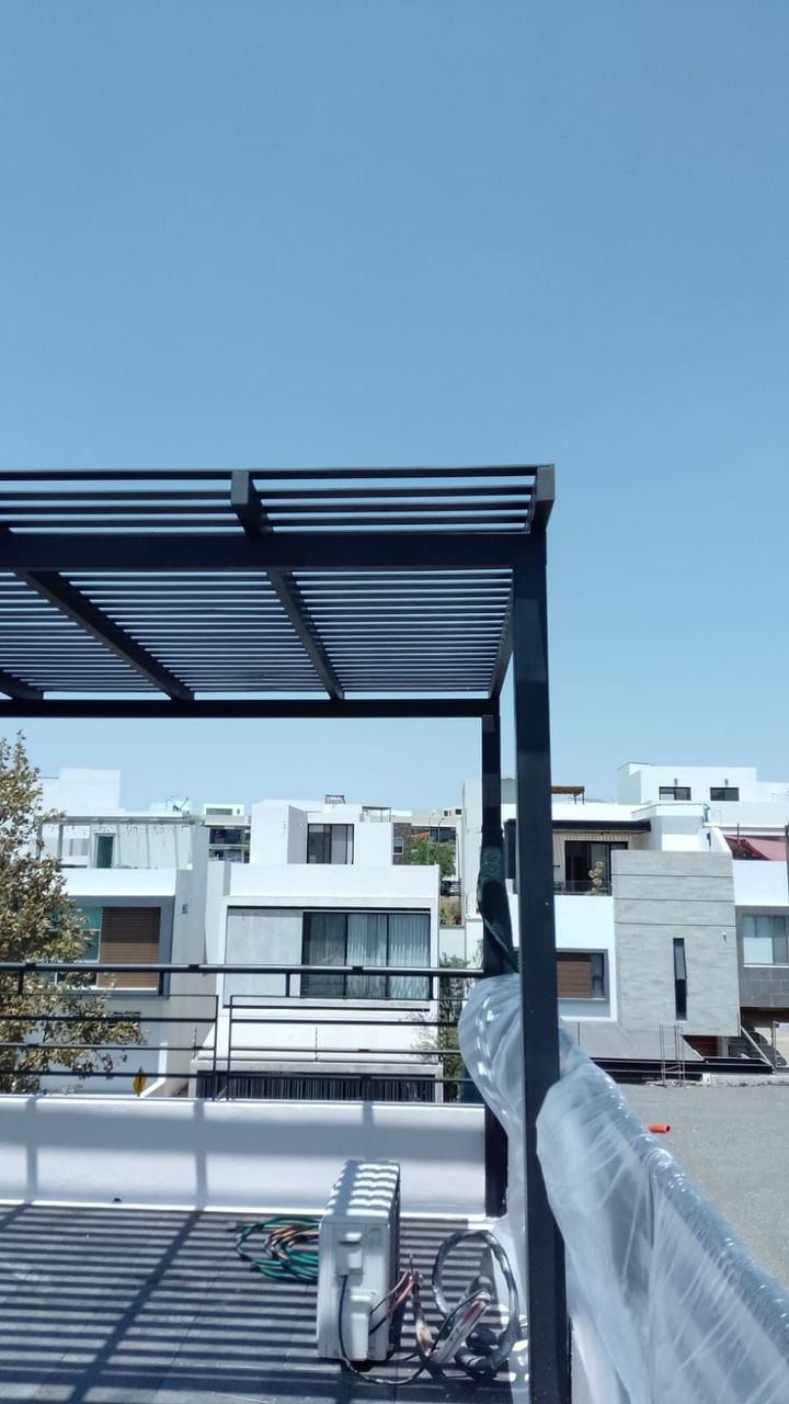 Pérgola de estructura metálica con perfilería negra en azotea de casa residencial